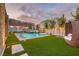 Backyard showcases a modern pool, spa with water features, and manicured landscaping under a colorful evening sky at 11912 Skyline Arch Ct, Las Vegas, NV 89138