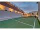 Outdoor tennis court featuring an entertaining area with manicured landscaping and outdoor lighting at 11912 Skyline Arch Ct, Las Vegas, NV 89138