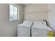 Bright laundry room featuring a washing machine, dryer, window, and a wire rack at 2586 Begonia Valley Ave, Henderson, NV 89074