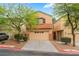 Two story home featuring a two-car garage, drought resistant landscaping and mature trees at 28 Yellow Flame Ave, North Las Vegas, NV 89084