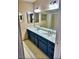 Bathroom featuring a dual sink vanity with blue cabinets, large mirrors, and a shower/tub combination at 3729 La Junta Dr, Las Vegas, NV 89120