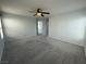 Large, gray bedroom with neutral carpet, ceiling fan, and doorway to the hall at 4749 Golden Shimmer Ave, Las Vegas, NV 89139