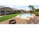 Fenced pool with tanning ledge surrounded by desert landscaping, green grass, and palm trees at 5586 Golden Leaf Ave, Las Vegas, NV 89122