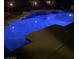 Backyard pool with a multi-tiered waterfall feature enhanced by custom lighting and privacy fence at 5586 Golden Leaf Ave, Las Vegas, NV 89122