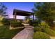 Landscaped backyard with a stone pathway leading to a covered seating area, perfect for outdoor gatherings at 6338 Skystone St, Las Vegas, NV 89135