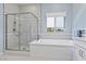 A bright bathroom boasts a glass-enclosed shower, a soaking tub, and light blue walls, creating a spa-like atmosphere at 6338 Skystone St, Las Vegas, NV 89135