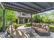 Inviting outdoor patio featuring comfortable seating under a pergola with lush landscaping and views of the home at 6338 Skystone St, Las Vegas, NV 89135