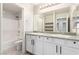 Bathroom with double sinks, granite countertops, a large mirror and tiled shower at 7733 Rosebark Cliffs St, North Las Vegas, NV 89084