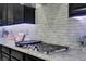 Close-up of a stainless steel stove top with a patterned backsplash and dark wood cabinets at 9654 Starfish Reef Way, Las Vegas, NV 89178