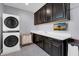 Well-organized laundry room with stacked washer/dryer, cabinets, counter space, and mounted TV at 9654 Starfish Reef Way, Las Vegas, NV 89178