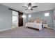 Comfortable main bedroom features a ceiling fan, soft carpet, and a sliding barn door to bathroom at 9654 Starfish Reef Way, Las Vegas, NV 89178