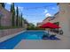 Relaxing pool area featuring lounge chairs, a vibrant red umbrella, and tasteful landscaping at 9654 Starfish Reef Way, Las Vegas, NV 89178