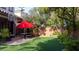 Backyard with picnic table and umbrella on artificial turf surrounded by lush landscaping at 11731 Longworth Rd, Las Vegas, NV 89135