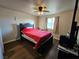 Bedroom featuring a large bed with a red blanket, a ceiling fan, natural light, and wood plank flooring at 1870 Upland Ave, Pahrump, NV 89048
