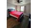 Cozy bedroom features a large bed with a red blanket, a ceiling fan, and wood plank flooring at 1870 Upland Ave, Pahrump, NV 89048