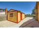 A yellow and red outbuilding with a red door sits on a concrete slab in the backyard at 1950 Abarth St, Las Vegas, NV 89142