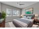 Staged bedroom featuring bright windows, a ceiling fan, a plush bed, and stylish decorations at 4829 E Beacon Ridge Dr, Pahrump, NV 89061