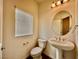Half bath featuring a toilet, pedestal sink, mirror, and a window at 5699 Woodchester Ave, Las Vegas, NV 89139