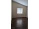 Cozy bedroom featuring a window, light-colored walls, a door, and dark wood flooring at 6113 Desert Haven Rd, Las Vegas, NV 89130