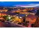 Aerial view of a residential neighborhood at dusk with city lights in the distance at 6630 Virtuoso Ct, Las Vegas, NV 89139