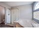 Bright bathroom featuring a glass-enclosed shower, soaking tub, and a unique arched window for natural light at 6630 Virtuoso Ct, Las Vegas, NV 89139