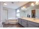 Bathroom with a soaking tub, glass-enclosed shower, double vanity, and arched window for natural light at 6630 Virtuoso Ct, Las Vegas, NV 89139