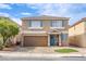 Two-story home with tan exterior, brown garage door, blue shutters, and manicured landscaping at 6630 Virtuoso Ct, Las Vegas, NV 89139