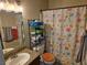 Functional bathroom with granite countertop vanity, storage shelves, and a bright floral shower curtain at 6800 E Lake Mead Blvd # 1126, Las Vegas, NV 89156