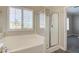 This bright bathroom features a white tiled soaking tub and glass enclosed shower at 6826 Dovecote Ave, North Las Vegas, NV 89084