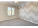 Bedroom with unique chevron accent wall, plush carpeting, and natural light at 6826 Dovecote Ave, North Las Vegas, NV 89084