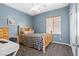 Cozy bedroom featuring blue walls, a wooden bed frame, and a ceiling fan with lighting at 7252 Royal Melbourne Dr, Las Vegas, NV 89131