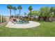 Lush backyard with a custom pool featuring a rock waterfall, palm trees, and green grass at 8970 Lansberry Ct, Las Vegas, NV 89147