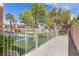 Fenced backyard featuring lush green grass and mature trees under a bright blue sky at 8970 Lansberry Ct, Las Vegas, NV 89147