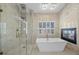 Bathroom featuring soaking tub, glass shower, fireplace, and modern tile at 8970 Lansberry Ct, Las Vegas, NV 89147
