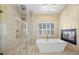 Luxurious bathroom featuring a soaking tub, fireplace, and a glass-enclosed shower with tiled walls at 8970 Lansberry Ct, Las Vegas, NV 89147