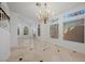Spacious living room with large windows, fireplace, and decorative chandelier with stone tile floors at 8970 Lansberry Ct, Las Vegas, NV 89147