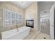 Luxurious bathroom boasting a soaking tub, plantation shutters, and fireplace at 8970 Lansberry Ct, Las Vegas, NV 89147
