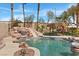Beautiful pool with rock waterfall and slide, complemented by a cozy tiki hut and lush landscaping at 8970 Lansberry Ct, Las Vegas, NV 89147