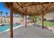 View from inside the tiki hut showcasing the pool with rock features and surrounding landscaped backyard at 8970 Lansberry Ct, Las Vegas, NV 89147