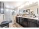 Bathroom featuring dual sinks, a large mirror, dark cabinets, and a glass enclosed shower at 9704 Morgan Creek Ct, Las Vegas, NV 89141