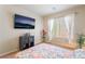 Bright bedroom featuring a window, TV, and floral bedding at 9704 Morgan Creek Ct, Las Vegas, NV 89141