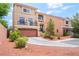 Two-story tan stucco home with a balcony, attached garage, and desert landscaping at 9704 Morgan Creek Ct, Las Vegas, NV 89141