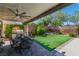 Charming backyard featuring a covered patio with a grill, a dining table, and a well-manicured lawn at 10420 Loma Portal Ave, Las Vegas, NV 89166