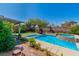 Beautiful backyard pool with a spa, covered patio, and lush landscaping, perfect for outdoor relaxation and entertainment at 10420 Loma Portal Ave, Las Vegas, NV 89166