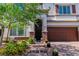 Beautiful two-story home with brick-accented entryway, brown garage door and colorful landscaping at 10420 Loma Portal Ave, Las Vegas, NV 89166
