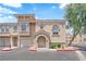 Inviting townhome with tan stucco, arched entryway, two car garage, and mature tree in a well-maintained community at 10550 W Alexander Rd # 2079, Las Vegas, NV 89129