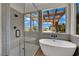 Modern bathroom featuring a soaking tub and walk-in shower with neutral toned tiling and outdoor views at 1984 Troon Dr, Henderson, NV 89074