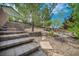 Multi-tiered backyard with stone steps, desert landscaping, and mature trees at 2621 Icy Moon St, Henderson, NV 89044