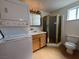 Bathroom with golden shower, wood vanity and countertop, toilet, and washer-dryer combo at 4831 W Bell Vista Ave, Pahrump, NV 89060