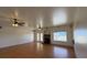 Open-concept living room featuring wood-look floors, ceiling fans, a brick fireplace, and double doors at 4831 W Bell Vista Ave, Pahrump, NV 89060